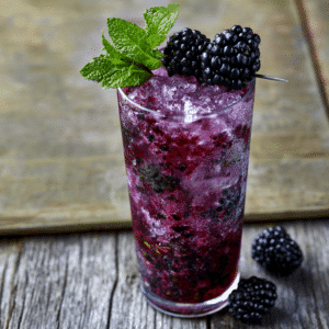Tall Blackberry Mojito Cocktail With Deep Purple Color, Crushed Ice, Fresh Mint, And Blackberry Garnish