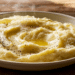 Creamy Mashed Potatoes Topped With Melted Butter, Black Pepper, And Grated Pecorino Romano In A White Bowl