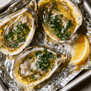 Six Baked Oysters On Half Shells With Golden Garlic Butter And Parsley On A Foil-Lined Baking Sheet