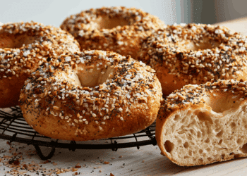 Golden Everything Bagels With Sesame Poppy Seeds And Coarse Salt On A Black Wire Cooling Rack