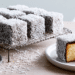 Classic Australian Lamington Recipe For A Delicious Dessert - Thefoodiebunch Coconut-Coated Chocolate Lamingtons On A Wire Rack And White Plate, One Halved Showing Golden Sponge Inside